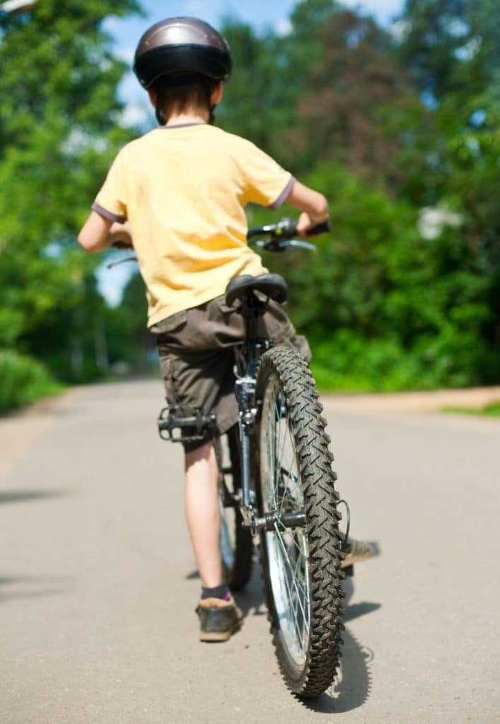 boy riding away on bicycle, paved road