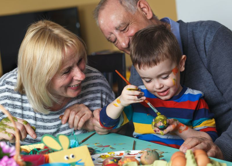 grandparents watching grandson paint easter eggs