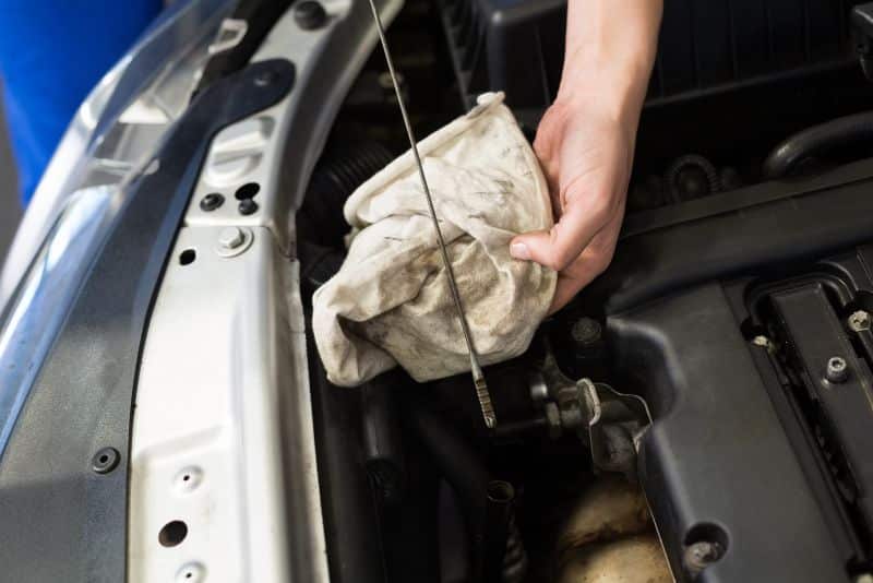 wiping dipstick to check oil in car