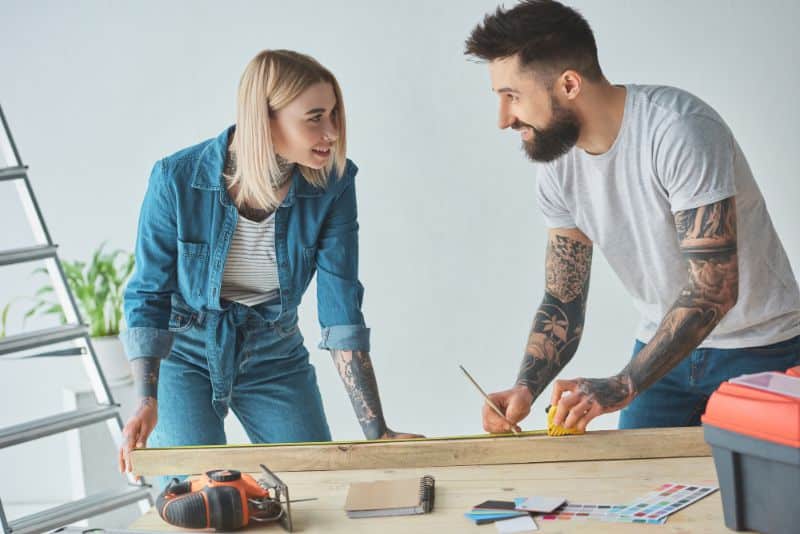 smiling tattooed couple working on home repairs together