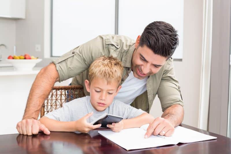smiling dad helping son with math homework