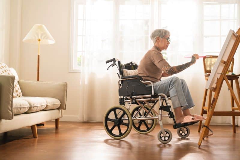 elderly woman in wheelchair painting on a canvas