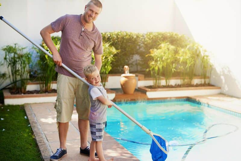a father and son cleaning the pool