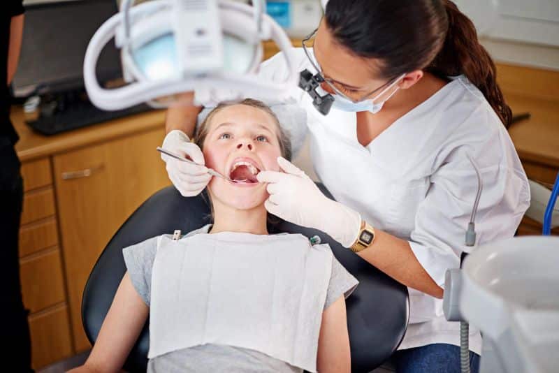 young girl getting her teeth looked at by female dentist