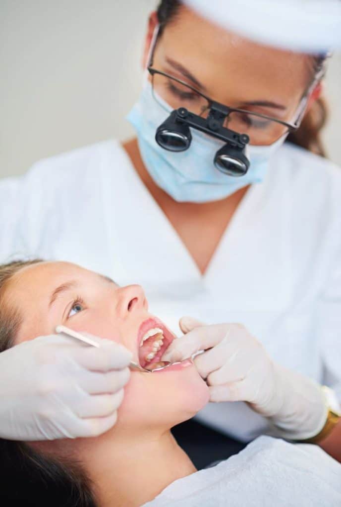 up close shot of female dentist looking at young girl's teeth