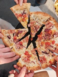 hands grabbing slices of pizza