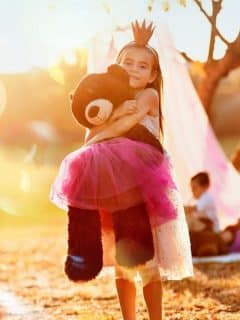 girl dressed as princess hugging teddy bear in tutu