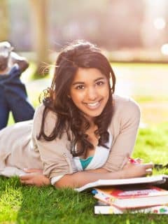 girl laying on the grass studying