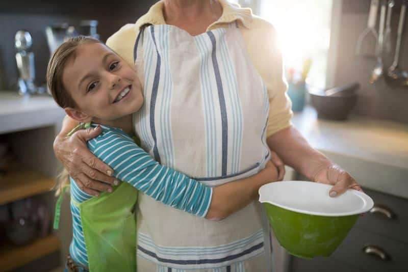 granddaughter hugging grandmother in kitchen