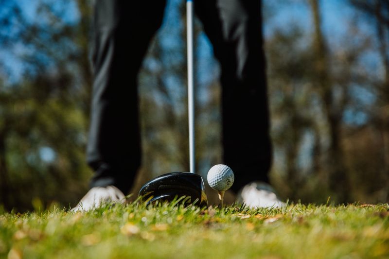 golf ball on tee with golf club ready to swing