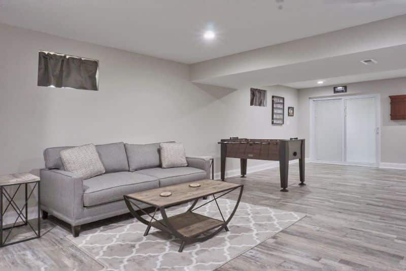 bright basement with sofa and game table