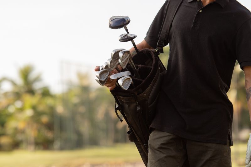 man carrying bag of golf clubs