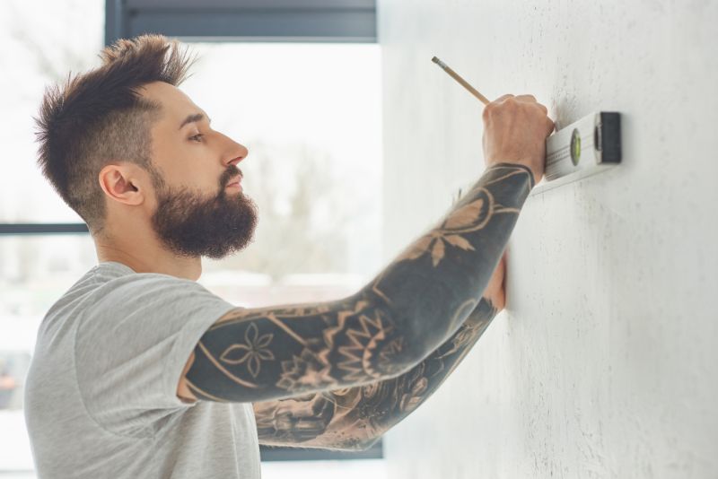 tattooed man with level placed against a wall