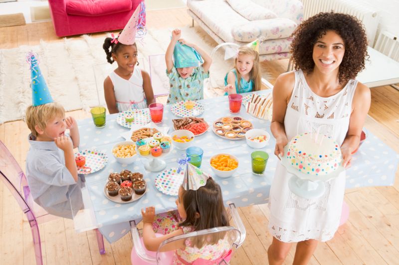 mom showing off cake at kid's birthday party