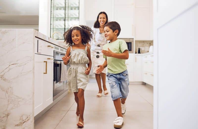 mom playfully chasing kids through kitchen