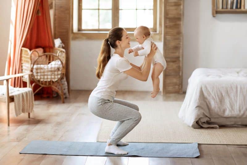 mom exercising while holding baby boy