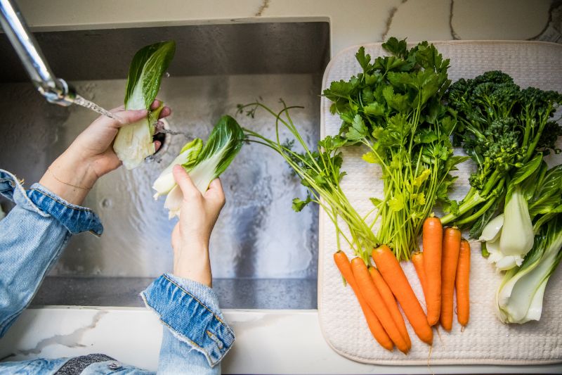 hands rinsing vegetables at the sink