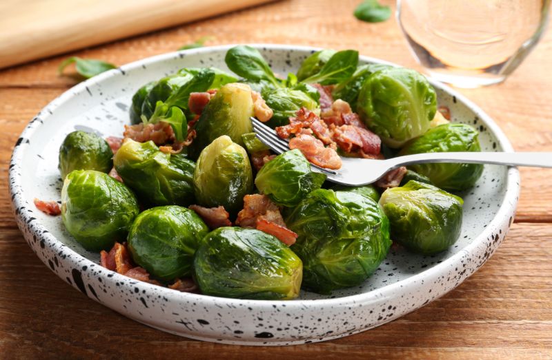 roasted brussels sprouts in bowl, wood background