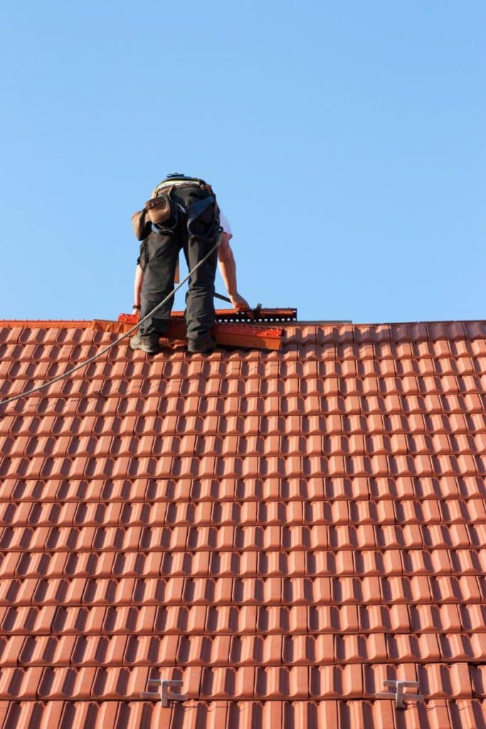 man on roof installing tiles