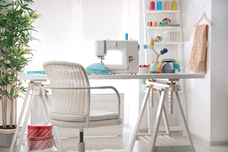 sewing room table with sewing machine on top and white chair in front