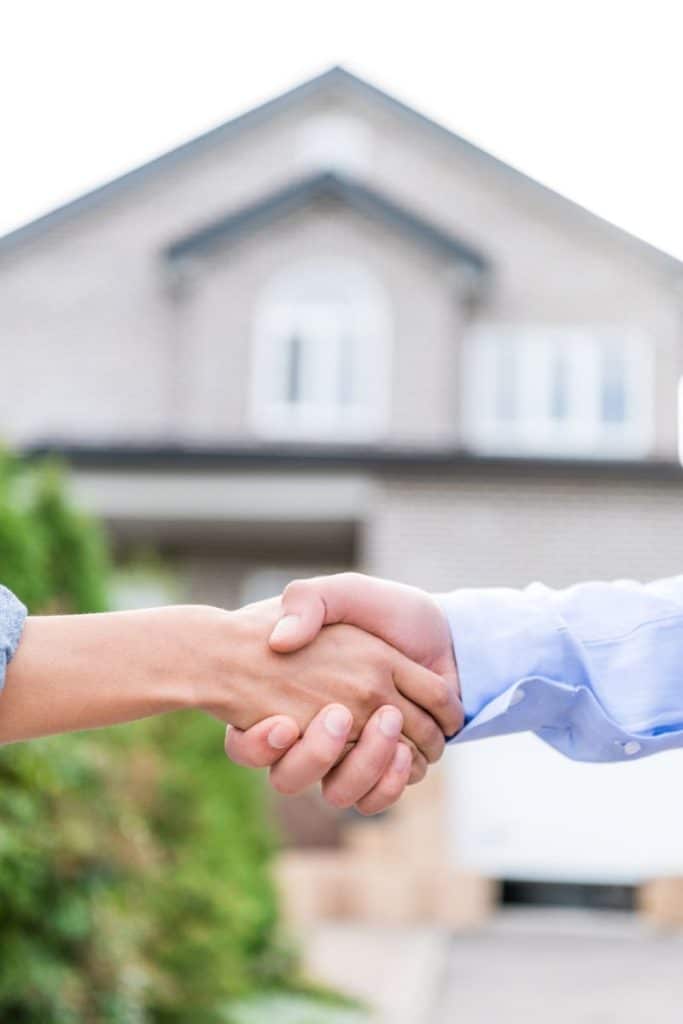 shaking hands in front of a home for sale