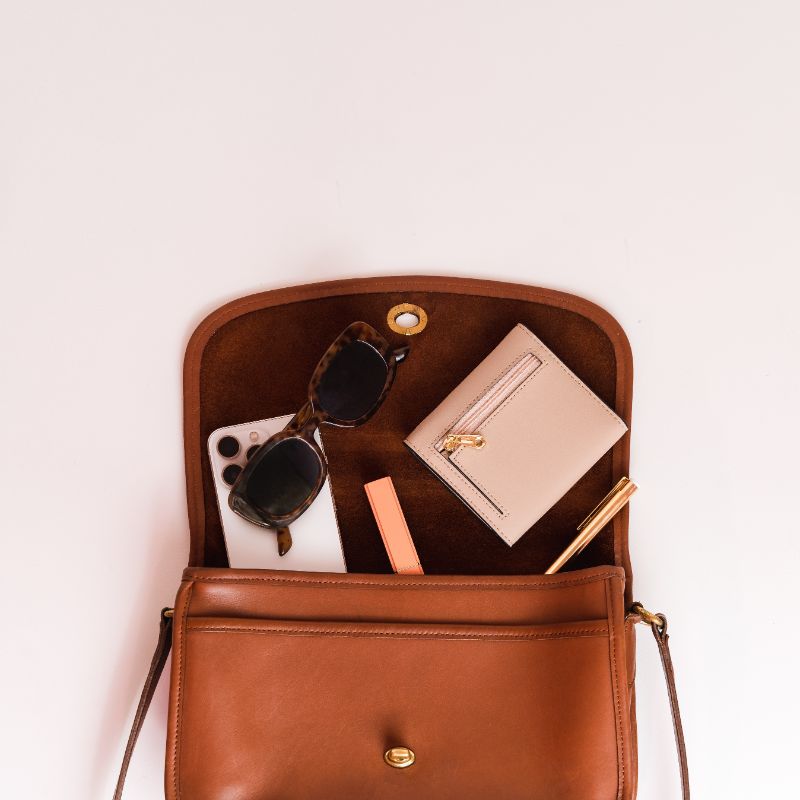 glasses, phone, wallet, etc. tucked into brown leather purse