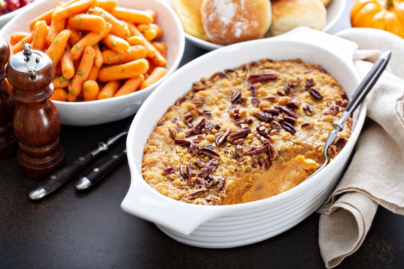 sweet potato casserole and roasted carrots in white serving dishes