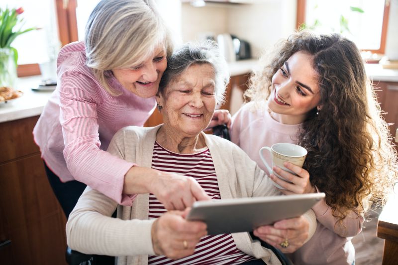 elderly woman using a tablet with her daughter and granddaughter