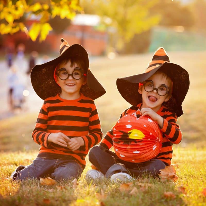 two brothers in grass wearing halloween hats and shirts