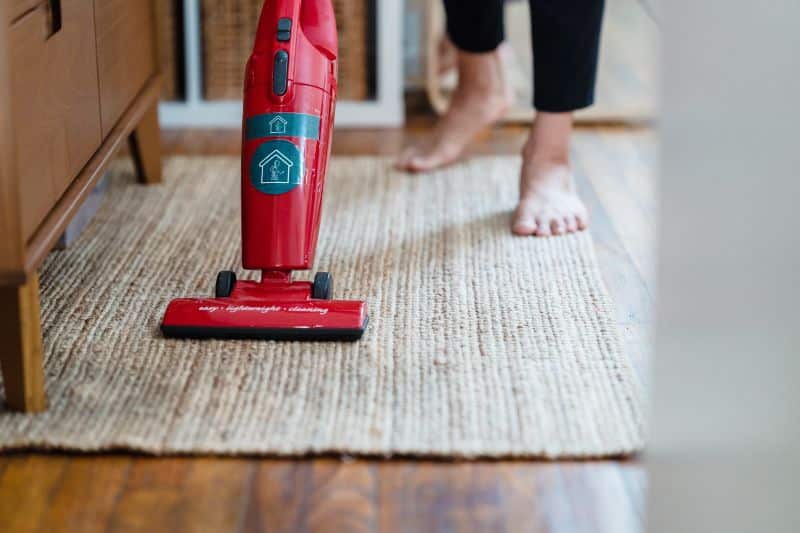 cleaning a rug with a red vacuum