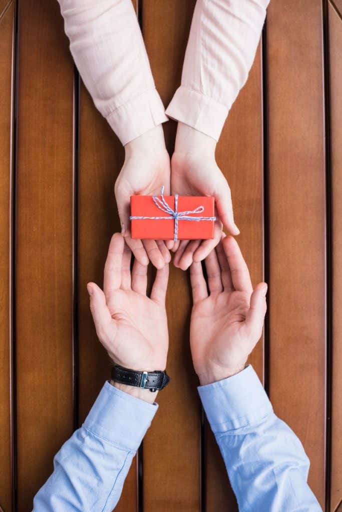 woman's hands passing gift to a man's hands