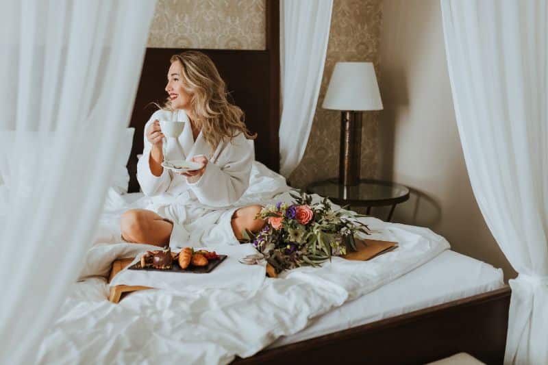 woman enjoying breakfast in bed on a four poster bed