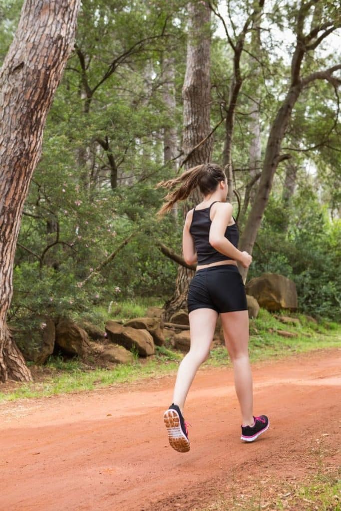 woman jogging along trail in woods