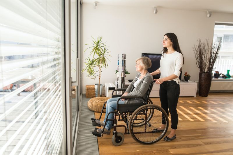 elderly woman in wheelchair and younger woman looking out window