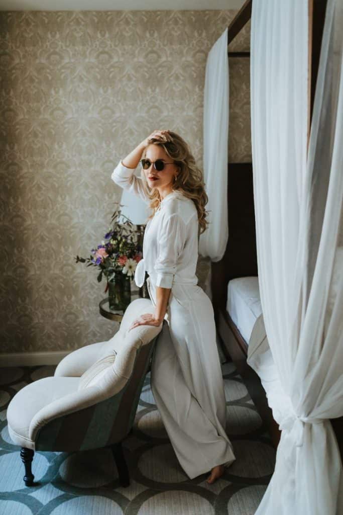 woman leaning against chair in bedroom with a four poster bed