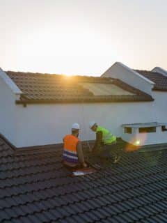 two workers on the roof of a house