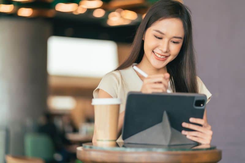 young woman smiling while looking at tablet