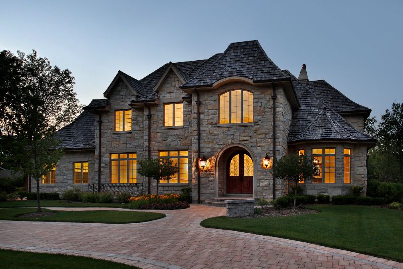 luxury stone home with windows lit up