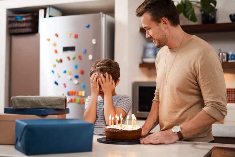 father surprising son with cake and gifts for birthday