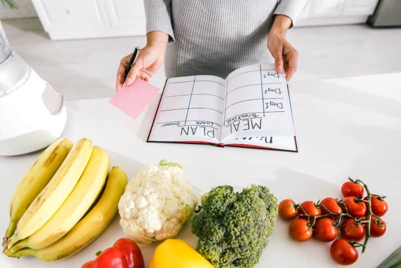 woman making a meal plan in a notebook