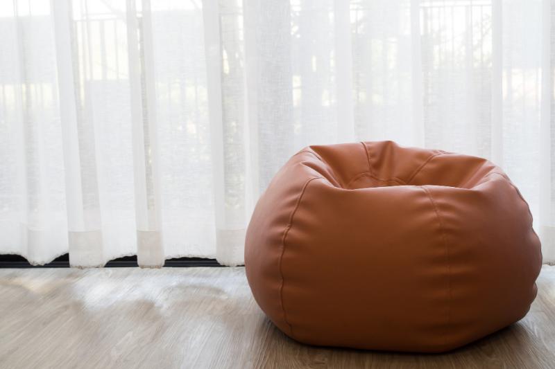 soft and smooth dark tan bean bag chair with sheer curtains behind