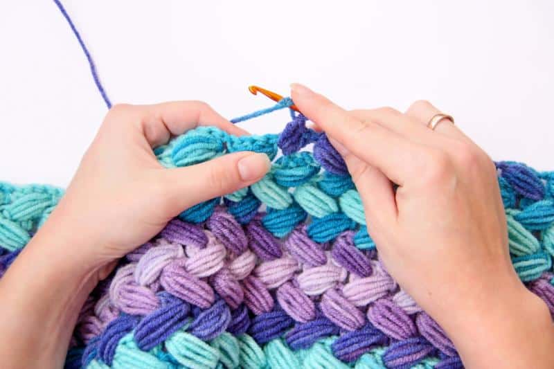 female hands crocheting a chunky blanket