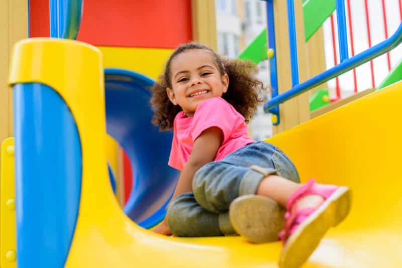 happy girl on playground slide