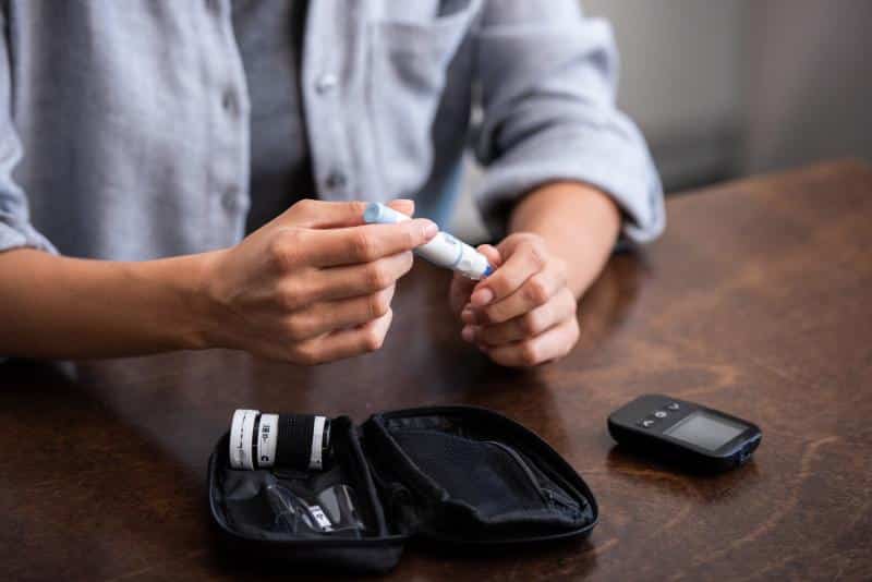 woman holding lancet from glucose testing kit