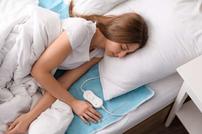 woman in bed with heating pad