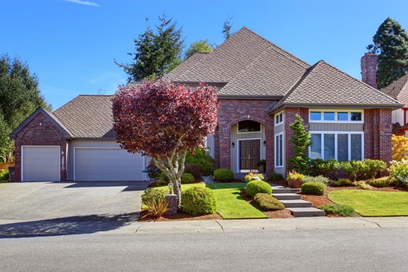 large brick home with three car garage and interesting roof