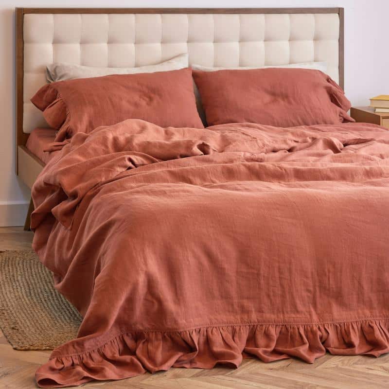 cozy bed with red-orange comforter and pillow cases