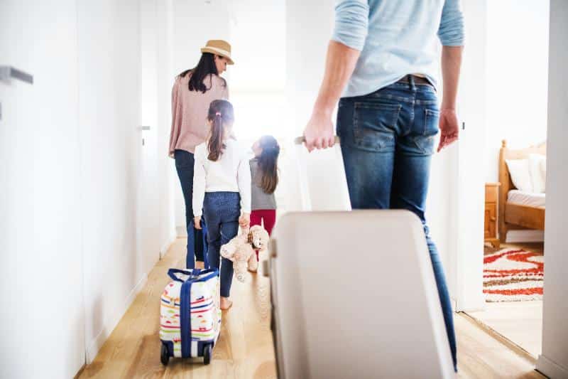 family of 4 walking down hallway with luggage before a trip
