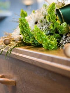 flowers with green ribbon on a wooden casket