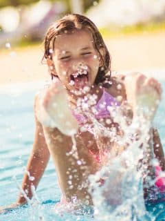 girl in pool splashing water with her feet
